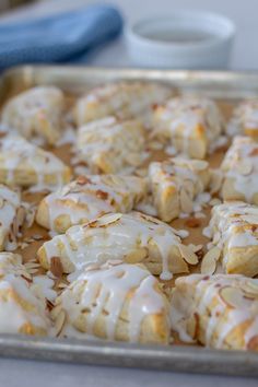 a pan filled with cinnamon rolls covered in icing and drizzled on top