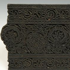 an intricately carved piece of wood with flowers and leaves in the center, on a white background