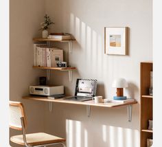 a laptop computer sitting on top of a wooden desk next to a shelf filled with books