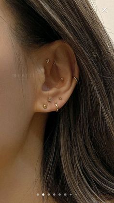 a close up of a person's ear with three small gold dots on it