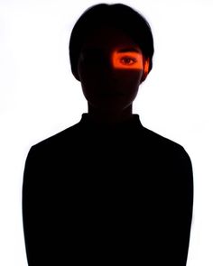 a person with an orange light on their face in front of a white background,