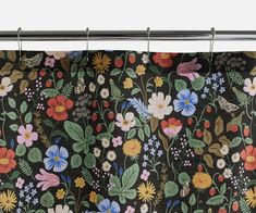 a black floral curtain hanging from a metal rod with flowers and leaves painted on it