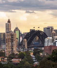 the city skyline is seen from across the river with an iron bridge in the foreground