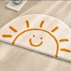 an orange and white towel with a smiling sun design on it's side, sitting on a bed