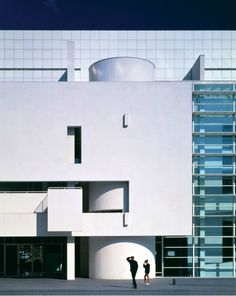 two people standing in front of a white building