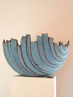 a blue bowl sitting on top of a white table next to a wall with a pink background