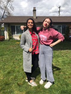 two women standing in front of a house