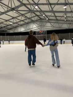 two people holding hands while skating on an ice rink