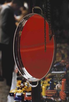 a red mirror hanging from the side of a metal pole