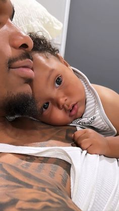 a man holding a baby while laying on top of a bed