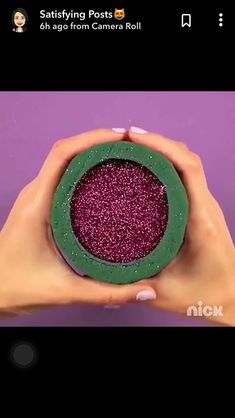 someone is holding up a green and purple object in their hands with glitter on it