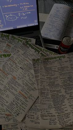 several pieces of paper sitting on top of a table next to a laptop computer and notebook