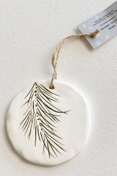 a white ceramic ornament with a pine tree design on it's side