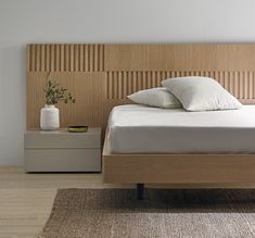 a bed with white pillows and wooden headboard