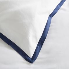 an unmade bed with white sheets and blue trim