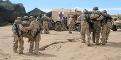 some soldiers are standing in the sand with their arms around each other