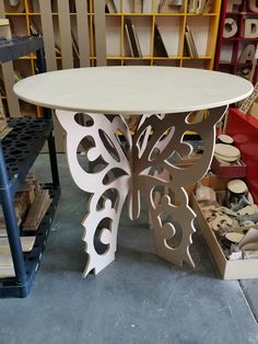 a white table sitting on top of a floor in a room filled with shelves and boxes