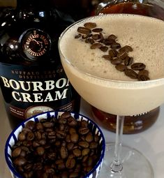 a drink in a glass with coffee beans on the rim next to a bowl of chocolate chips