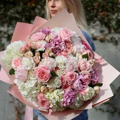 a woman holding a bouquet of pink and white flowers