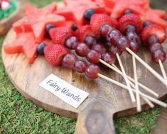 grapes, watermelon and strawberries are arranged on a cutting board with toothpicks