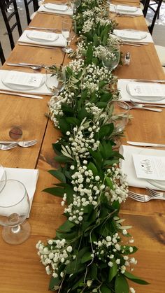 a long table is set with place settings and flowers on each side, along with silverware