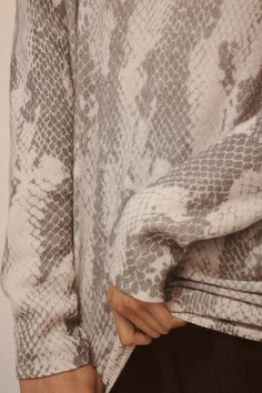 a close up of a person's hand on the back of a sweater that has an animal print pattern