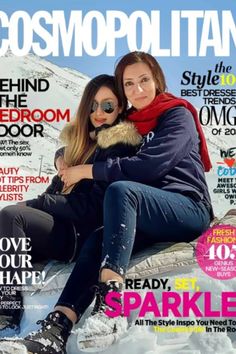 two women sitting on top of a snow covered hill with their arms around each other