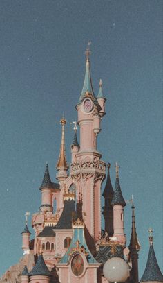 a pink castle with a clock on it's side in front of a blue sky