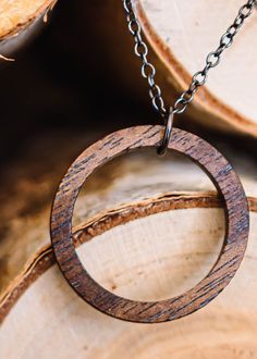 Walnut wood circle pendant is made from walnut wood that has been stained a bit darker than the natural wood. It's sanded smooth with 3 different grits of sandpaper. Chain and findings are gunmetal plated and come in 18in or 24in chain. Clasp is a spring ring. (model in pic is wearing the 18in chain). Circular pendant measures 1.25 in (33mm) Thickness of the pendant is 1/8in (3mm) approximately Please remove before showering/swimming. The polyurethane finish imparts a bit of water resistance, bu Handmade Round Wooden Jewelry, Earthy Wooden Jewelry Gift, Earthy Wood Jewelry Gift, Earthy Wood Jewelry As Gift, Earthy Natural Wood Jewelry For Gifts, Rustic Natural Wood Jewelry, Round Wood Jewelry As A Gift, Round Wooden Jewelry For Gifts, Round Wooden Jewelry Gift