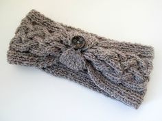 a gray knitted headband with a button on it's side and a knot at the end