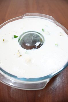 a bowl filled with white sauce on top of a wooden table