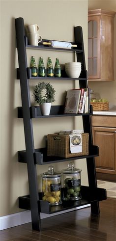 a black leaning shelf filled with books and other items next to a kitchen counter top