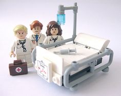 two legos are standing in front of a hospital bed with a doctor and nurse's stethoscope on it