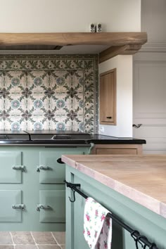 a kitchen with green cabinets and tile backsplashing on the wall above the stove