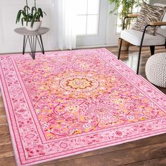 a pink area rug with an ornate design on the center and bottom, in front of a chair