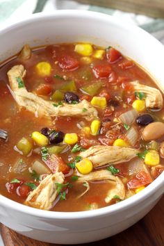 a white bowl filled with chicken and vegetable soup on top of a wooden cutting board