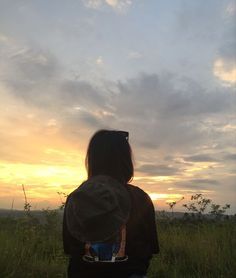 a person sitting in the grass watching the sun go down