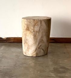 a marbled table sitting on top of a cement floor next to a white wall