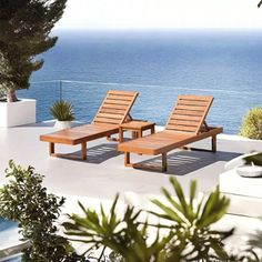 two wooden lounge chairs sitting on top of a patio