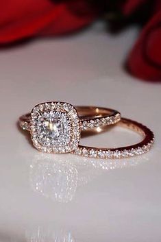 a close up of a diamond ring on a table with red roses in the background