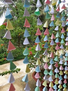 many colorful paper umbrellas hanging from a tree