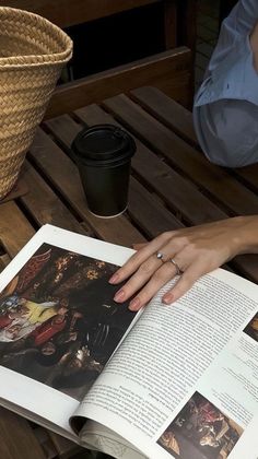 a person sitting at a table with an open book in front of them and a basket on the side