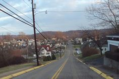 an empty street with houses and power lines on both sides in the distance is a small town