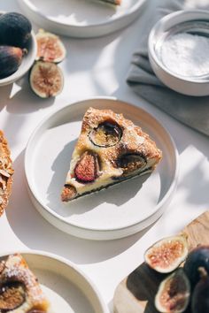 a slice of pie on a plate with some figs and other plates around it