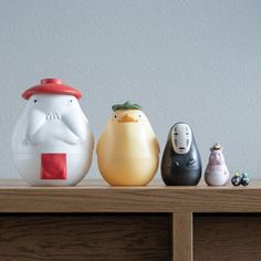 three ceramic figurines sitting on top of a wooden shelf next to each other