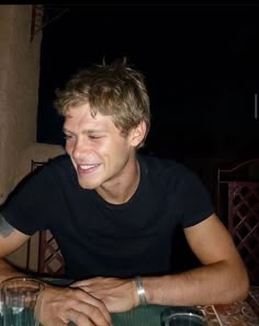 a young man sitting at a table smiling