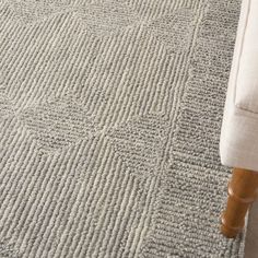 a white couch sitting on top of a wooden floor next to a rug covered in small squares