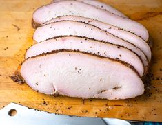 sliced meat sitting on top of a wooden cutting board