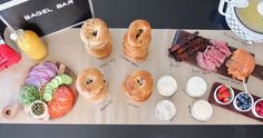 an assortment of pastries and desserts on a table with a bagel bar sign in the background