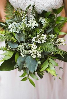 a bride holding a bouquet of flowers and greenery